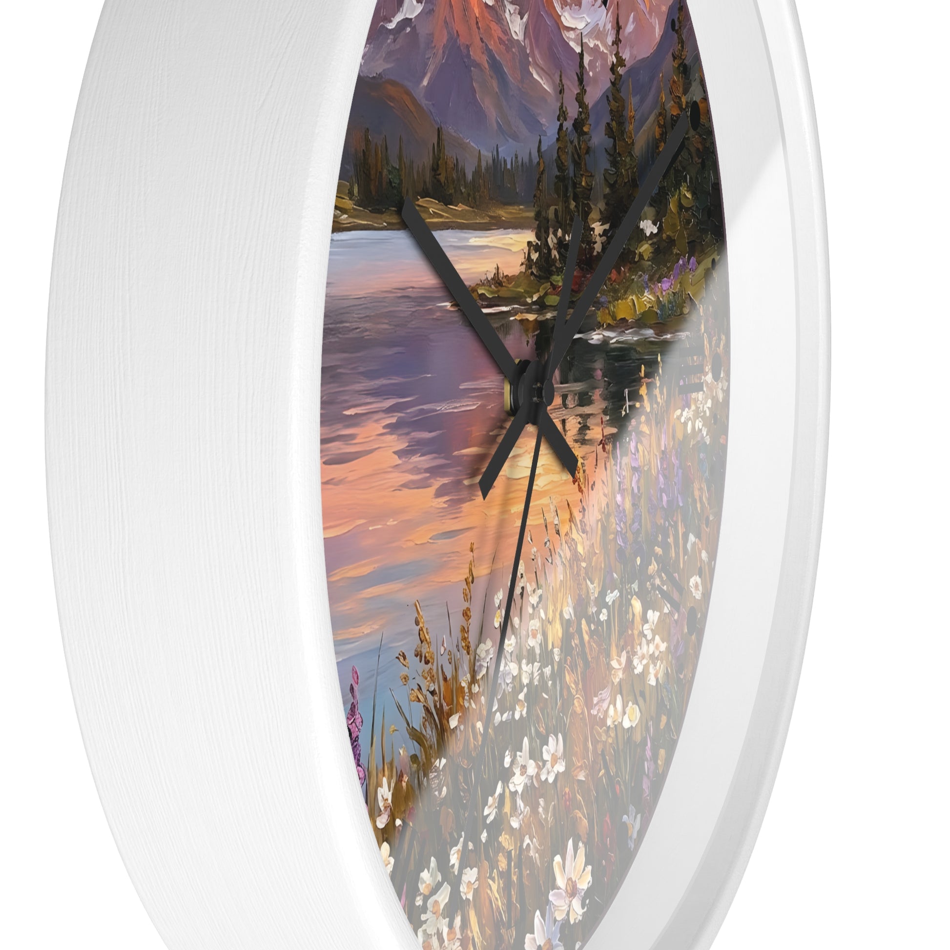 Round wall clock with a white frame and a scenic landscape print featuring a lake, mountains, trees, and wildflowers, shown against a plain white background.