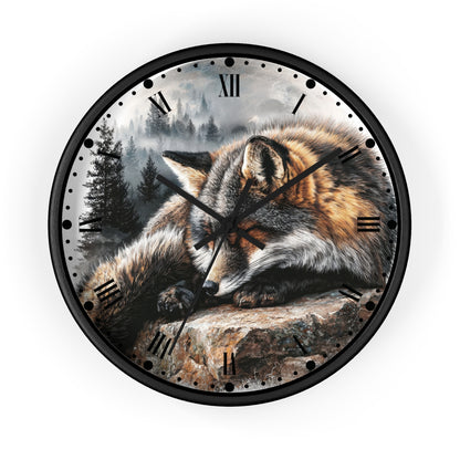 Round wall clock with a black frame and a printed dial showing a sleeping fox resting on a rock in a misty forest scene. The clock has black Roman numerals and black hands, photographed against a plain white background.