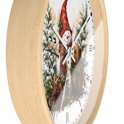 Round wall clock with a light natural wood frame and a festive printed face showing a snowman in a red hat among evergreen branches and a brown bear, on a white background.