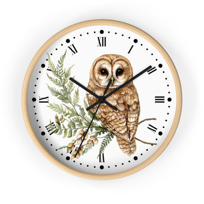 A round wall clock with a light wood frame, featuring a white dial decorated with a detailed illustration of a brown owl perched on a branch with green leaves. The clock has black Roman numerals and black hands, shown against a plain white background.