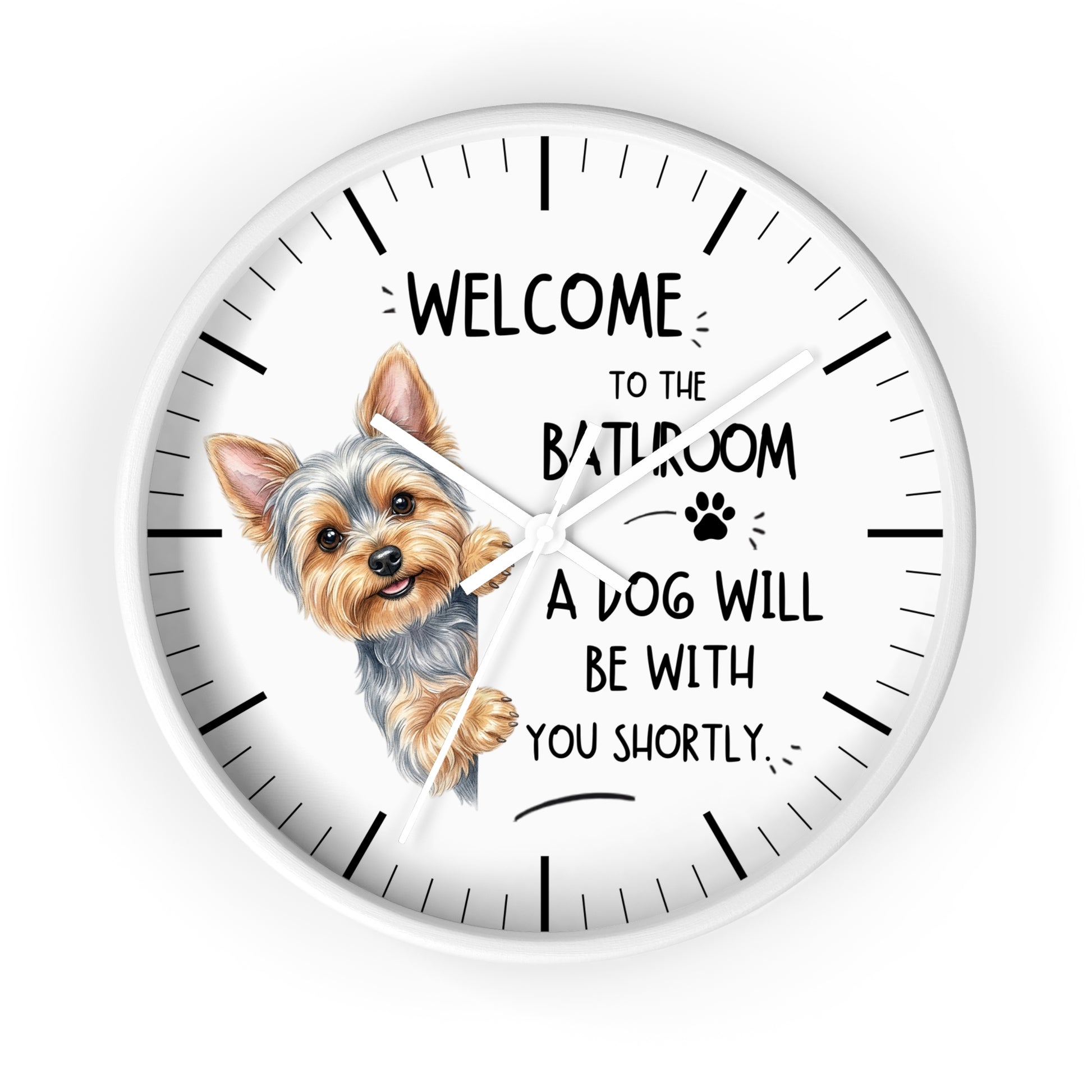 A round white wall clock with a black hand-drawn style outline frame, black hour markers, and a printed illustration of a Yorkshire Terrier peeking from behind the word 'BATHROOM' in a humorous quote that reads 'WELCOME TO THE BATHROOM A DOG WILL BE WITH YOU SHORTLY'.