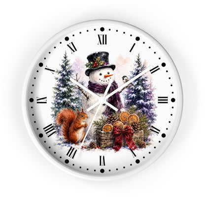 A round white wall clock with black Roman numerals and markers, featuring a festive winter illustration of a snowman, a squirrel, evergreen trees, and gift baskets on the face.