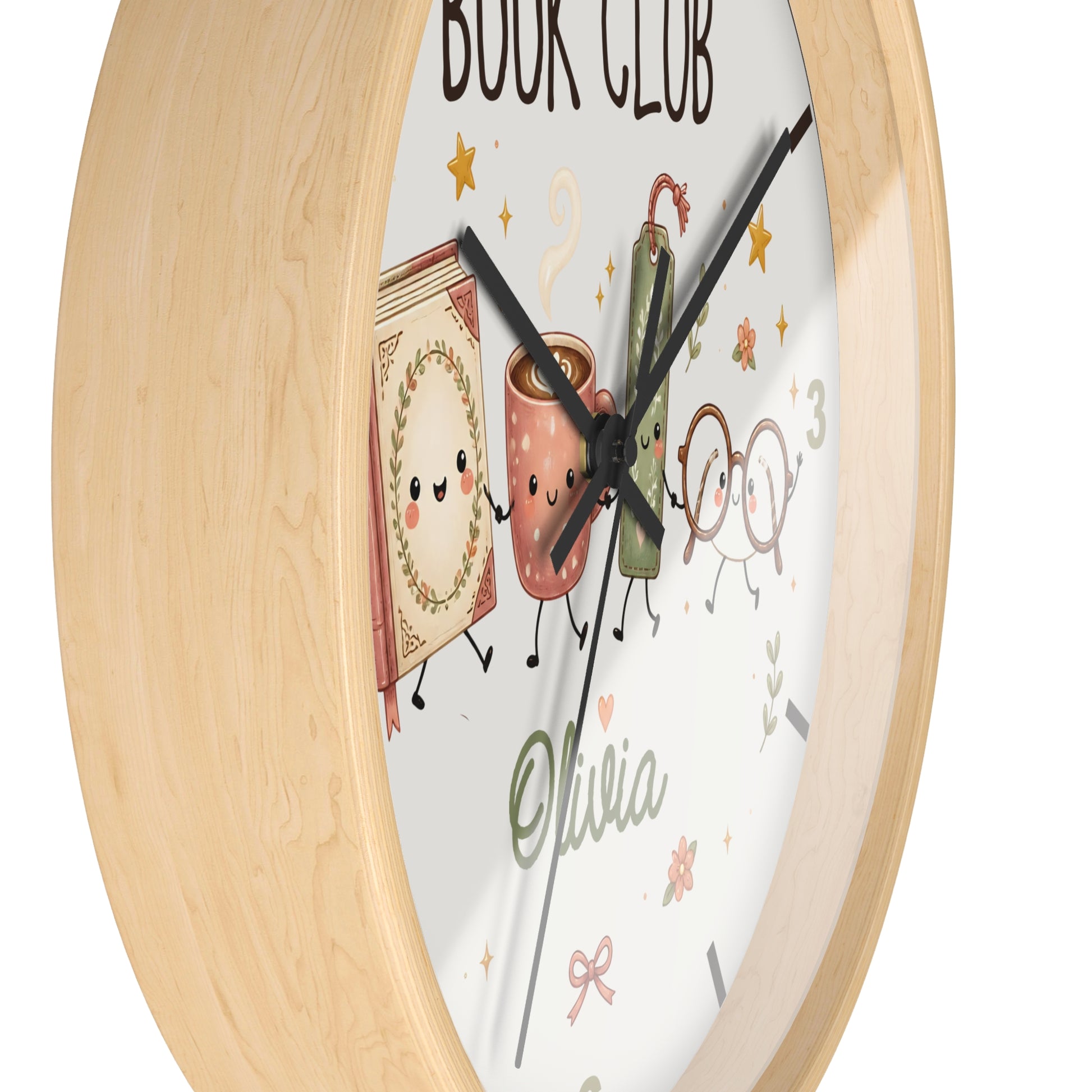 A round wall clock with a light natural wood frame and a white face featuring cute illustrated book and coffee cup characters, black hands, and the text 'BOOK CLUB' and 'Olivia'.