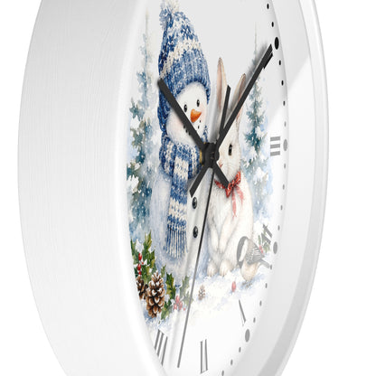 A round white wall clock with a winter illustration on the face, showing a snowman in a blue knit hat and scarf next to a white rabbit in snow, with black hands and Roman numerals.