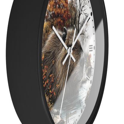 A round wall clock with a black frame and a printed nature scene featuring a capybara, autumn trees, and water. The clock has white hands and black Roman numeral hour markers on a white face, shown against a plain white background.