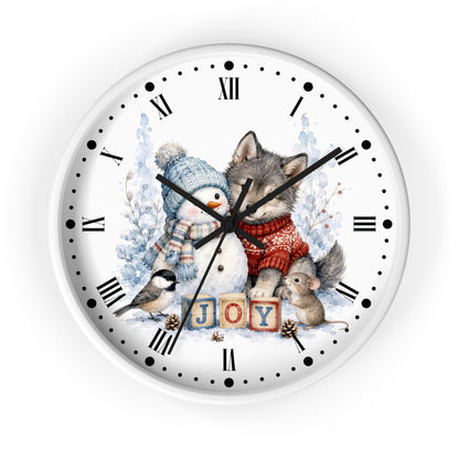 A round wall clock with a white face featuring a winter illustration of a wolf, a snowman, a small bird, and a mouse around the word 'JOY' in wooden blocks, with black Roman numerals and hands.