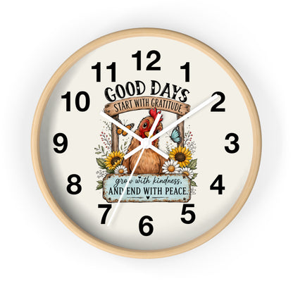 A round wall clock with a light natural wood frame and a cream-colored face. The clock face features a central illustration of a brown chicken surrounded by sunflowers, a butterfly, and a banner that reads 'GOOD DAYS START WITH GRATITUDE' and 'grow with kindness AND END WITH PEACE'.