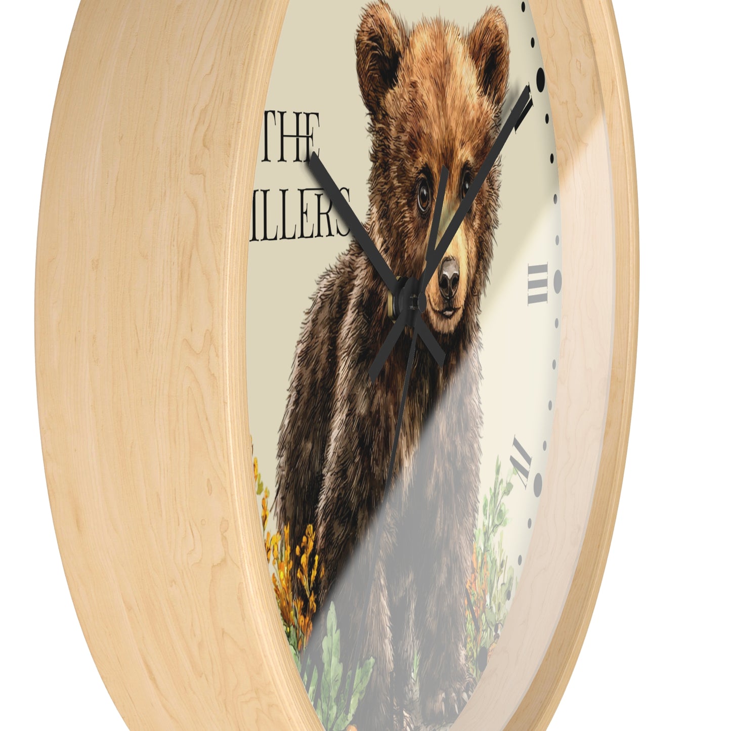 Round wall clock with a light natural wood frame and a printed face featuring a brown bear illustration and the text 'THE ILLERS'.