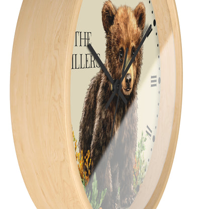 Round wall clock with a light natural wood frame and a printed face featuring a brown bear illustration and the text 'THE ILLERS'.