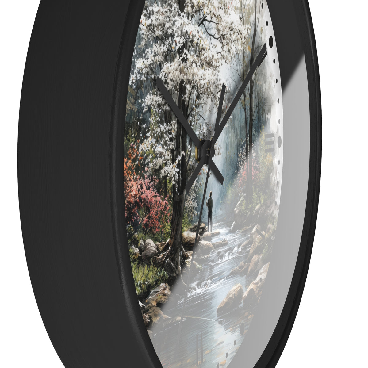 Round wall clock with a black frame and a printed scenic dial showing a forest stream, white blossoms, and a small figure, photographed against a white background.