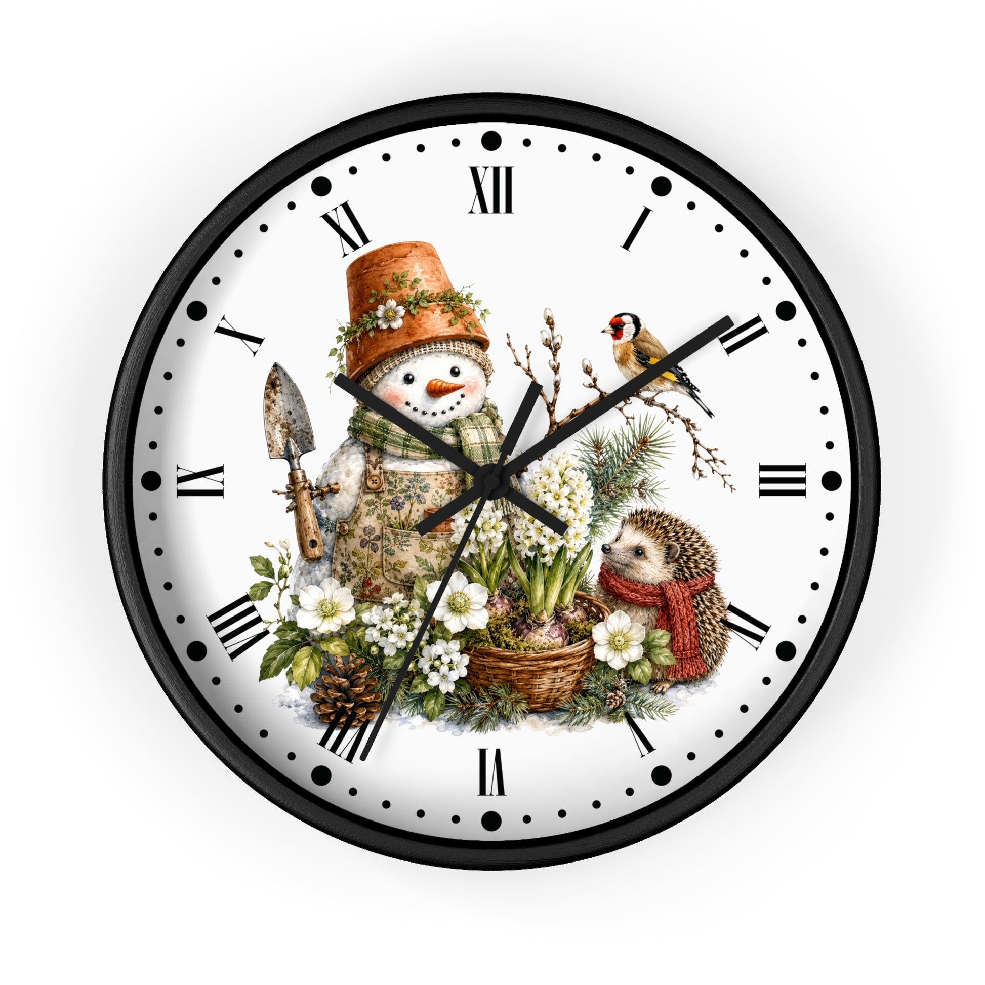 A round wall clock with a black frame and a white face featuring a whimsical winter garden illustration. The design includes a snowman wearing a terracotta pot hat and holding a trowel, a small bird perched on a branch, a hedgehog in a red scarf, white flowers, pinecones, and green foliage.