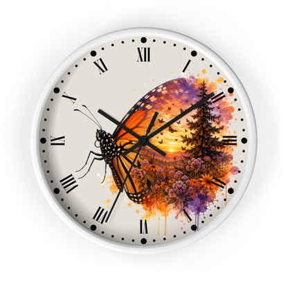 A round wall clock with a white frame and a cream-colored face featuring a watercolor-style butterfly and forest sunset design in orange, purple, and black.