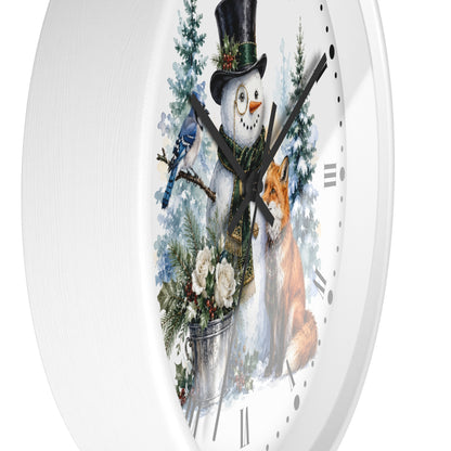 A white round wall clock with a festive winter illustration on the face, featuring a snowman in a black top hat, a bluebird, a fox, evergreen trees, and a bucket of flowers.