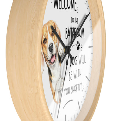 A round wall clock with a light natural wood frame and a white face featuring a beagle illustration and the text 'WELCOME TO THE BATROOM A DOG WILL BE WITH YOU SHORTLY'.