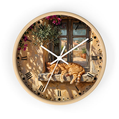 Round wall clock with a light wood frame and a printed scene of a sleeping orange tabby cat on a stone ledge in front of a window, with white clock hands and black Roman numerals.