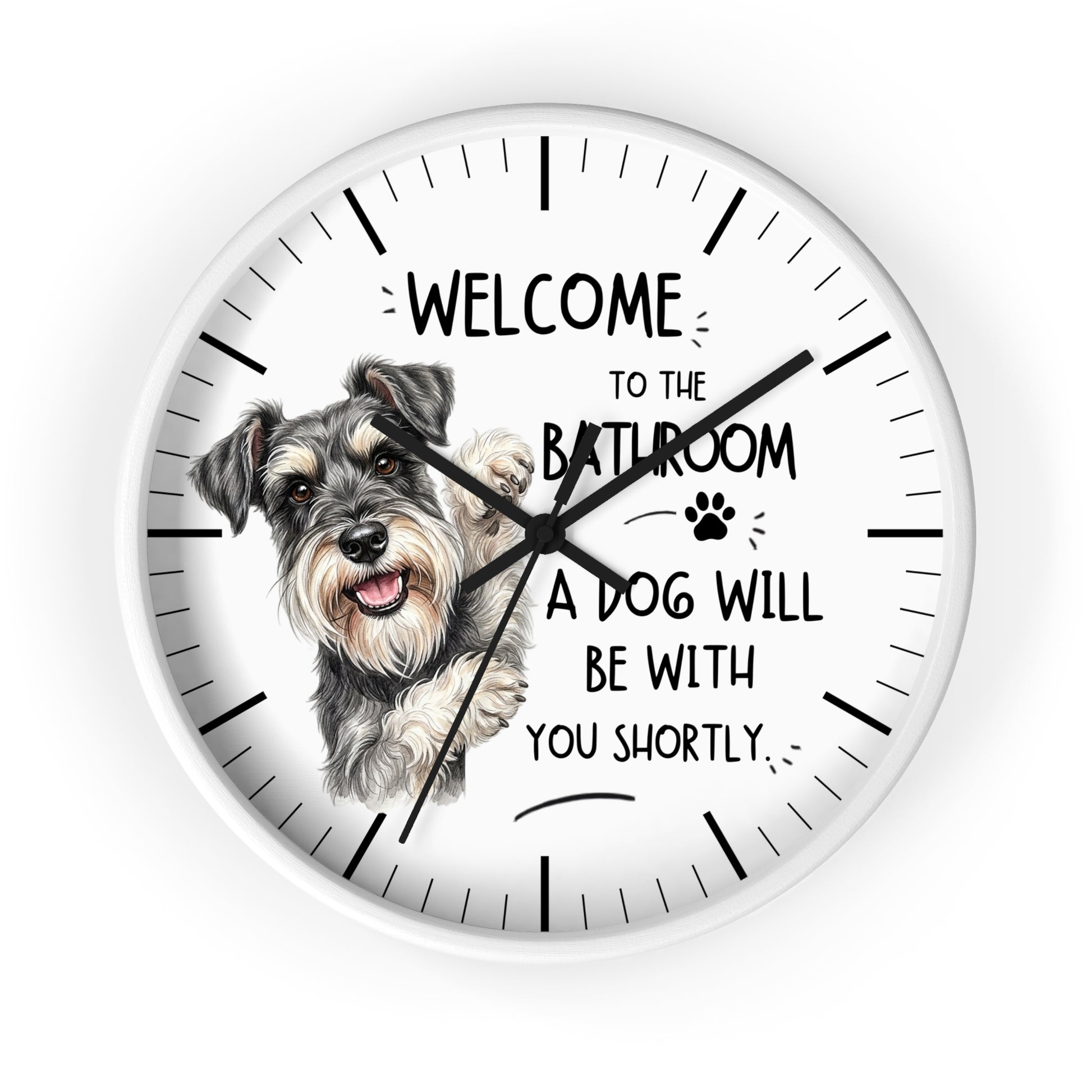 A round white wall clock with black hands and hour markers, featuring a printed illustration of a scruffy dog and the text 'WELCOME TO THE BATHROOM A DOG WILL BE WITH YOU SHORTLY.' on a white background.