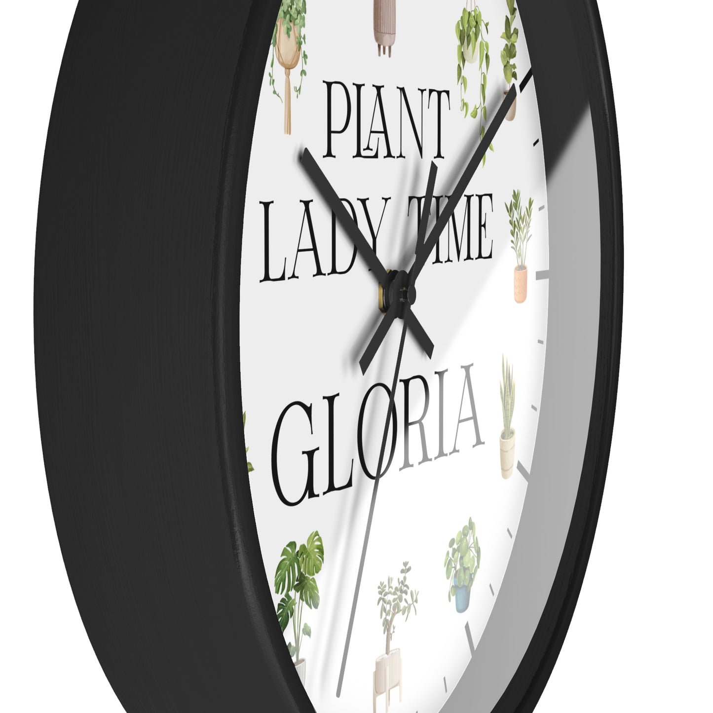 A close-up of a round wall clock with a black frame and a white face featuring the text 'PLANT LADY TIME GLORIA' and small potted plant illustrations.