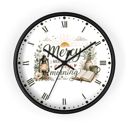 A round wall clock with a black frame and a white face featuring a vintage-style morning illustration. The design includes the words 'Mercy' and 'enjoy your morning' with a lantern, flowers, an open book, and a mug.