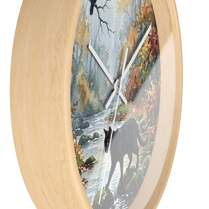 Round wall clock with a light natural wood frame and a printed scenic dial showing a forest stream, autumn foliage, and a dark cat silhouette, photographed on a white background.