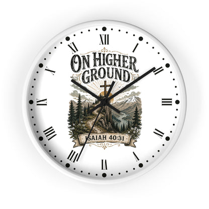 A round white wall clock with black Roman numerals and hands, featuring a scenic mountain and forest illustration in the center with the text 'ON HIGHER GROUND' and 'SAITH 40:31'.