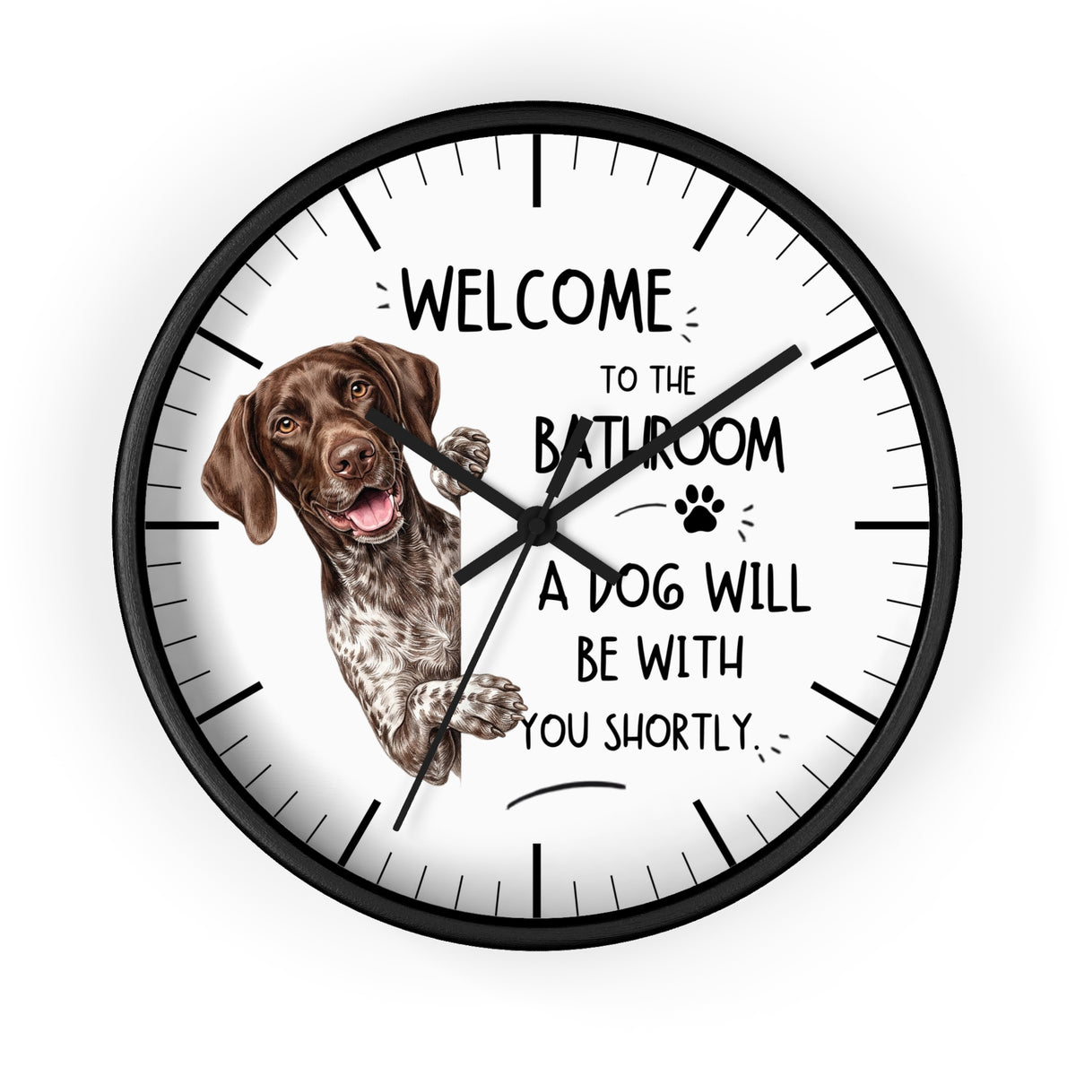 A round wall clock with a black frame and white face, featuring a German Shorthaired Pointer dog illustration and the humorous text 'WELCOME TO THE BATHROOM A DOG WILL BE WITH YOU SHORTLY.'.
