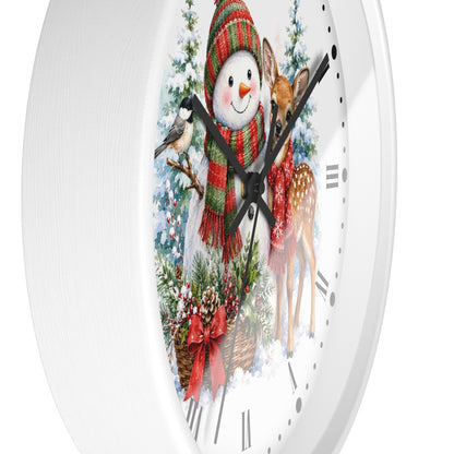 A white round wall clock with a festive winter illustration on the face, featuring a snowman in a red and green striped hat and scarf, a deer, a bird, and evergreen branches, shown against a plain white background.