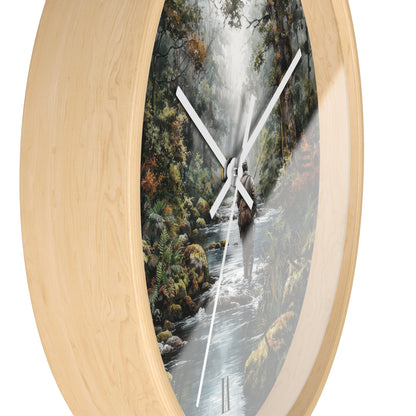 Round wall clock with a light natural wood frame and a printed scenic dial showing a forest stream with a waterfall and a person in a canoe, photographed on a white background.