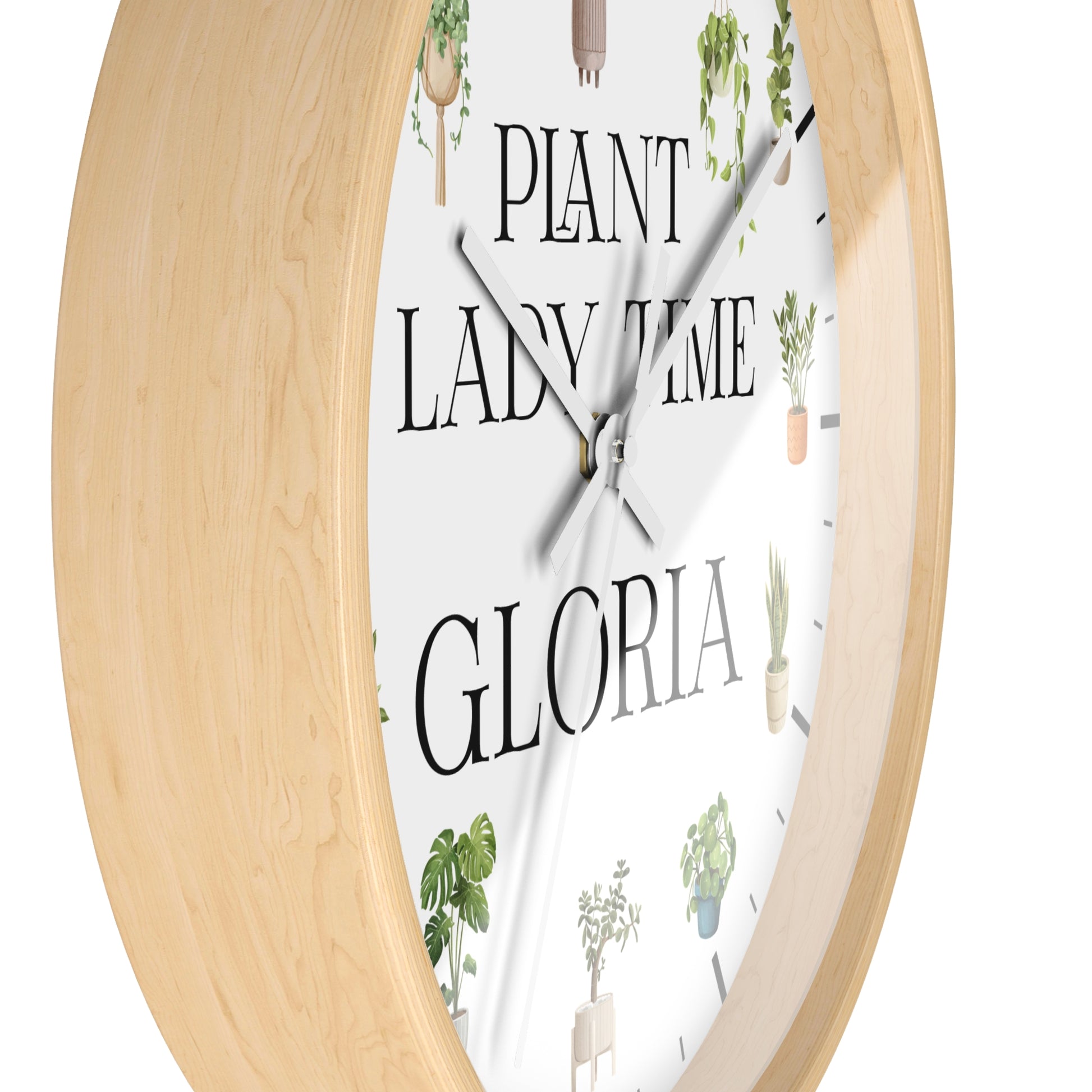 Round wall clock with a light natural wood frame and a white face featuring the text 'PLANT LADY TIME GLORIA' and small potted plant illustrations.