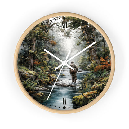 A round wall clock with a light natural wood frame, featuring a scenic print of a fisherman standing in a flowing stream surrounded by a dense forest. The clock has white hands and black Roman numeral hour markers.