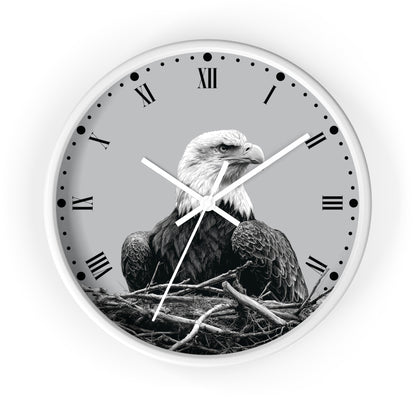 A round wall clock with a white frame and a monochrome photograph of a bald eagle sitting in a nest on the clock face, with black Roman numerals and white hands against a light gray background.