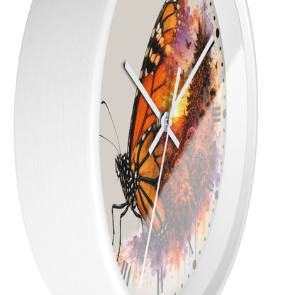 A round white wall clock with a printed design of an orange and black butterfly over a colorful watercolor splash background.