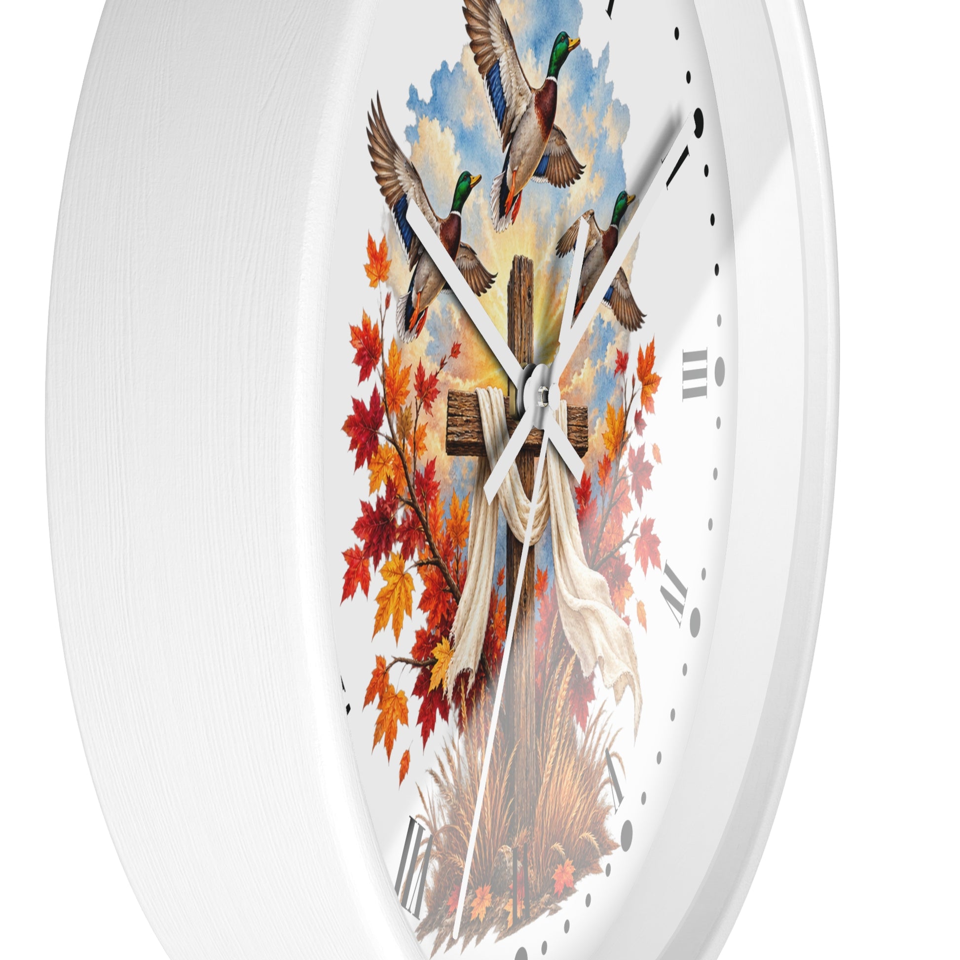 A white round wall clock with a detailed autumn-themed illustration on the face, featuring mallards, fall leaves, a rustic cross, and a draped white cloth, shown against a plain white background.