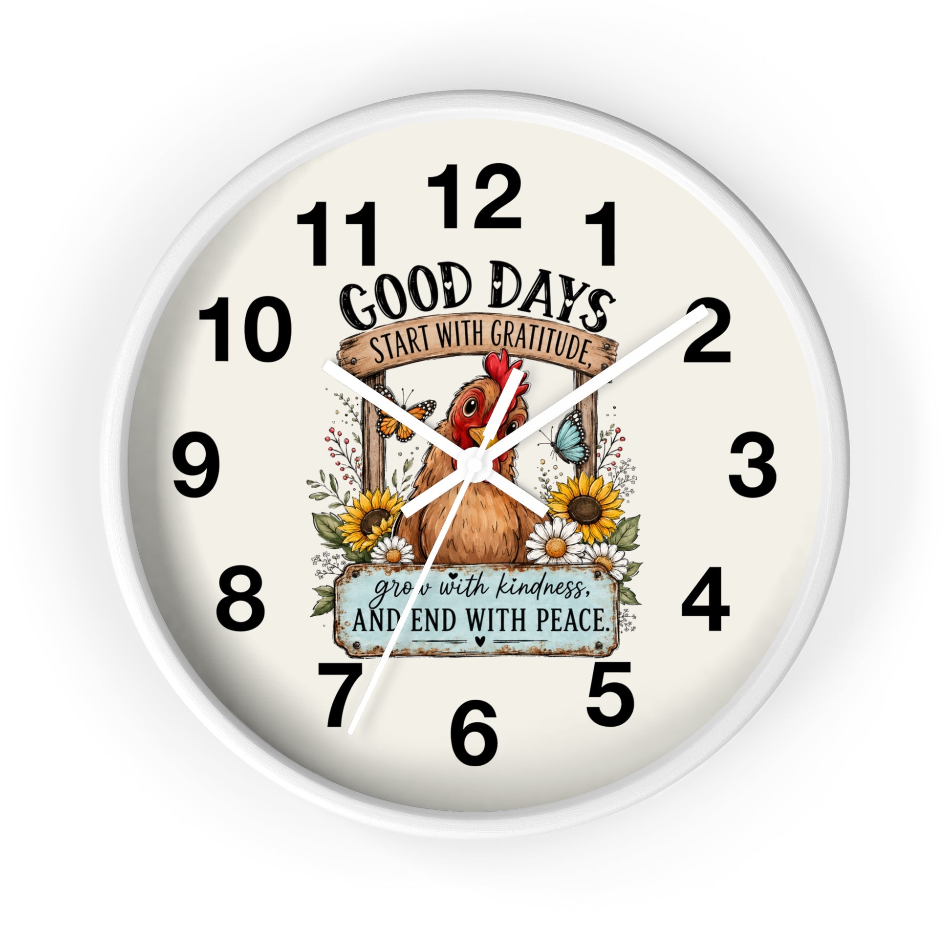 A round wall clock with a white frame and an off-white face, featuring a central illustration of a brown chicken surrounded by sunflowers and a butterfly. The clock face includes the text 'GOOD DAYS START WITH GRATITUDE' and 'grow with kindness AND END WITH PEACE' along with black numerals from 1 to 12.
