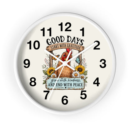 A round wall clock with a white frame and an off-white face, featuring a central illustration of a brown chicken surrounded by sunflowers and a butterfly. The clock face includes the text 'GOOD DAYS START WITH GRATITUDE' and 'grow with kindness AND END WITH PEACE' along with black numerals from 1 to 12.