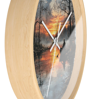 Oval wall clock with a light natural wood frame and a printed scenic dial showing a forest lake sunset with white clock hands.