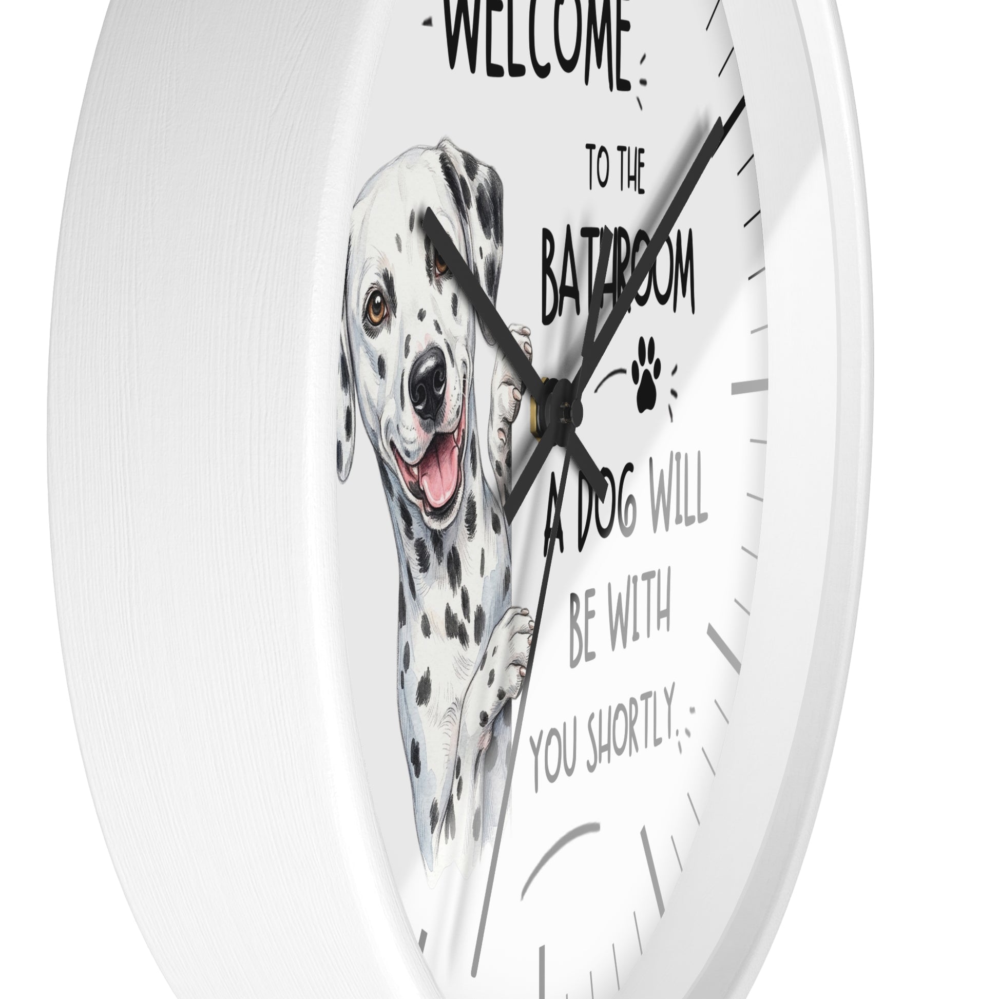 A white round wall clock with a printed illustration of a Dalmatian dog and the humorous text 'WELCOME TO THE BATHROOM A DOG WILL BE WITH YOU SHORTLY' on a clean white background.