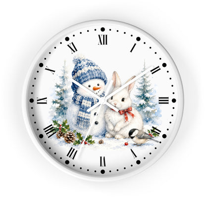 A round white wall clock featuring a winter holiday illustration on the face, showing a snowman in a blue knit hat and scarf next to a white rabbit with a red bow, with snowy trees and pinecones around them. The clock has black Roman numerals and black hour markers.