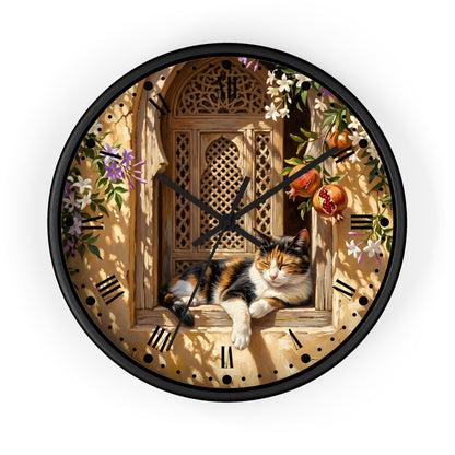 A round wall clock with a black frame and a printed illustration of a calico cat lounging on a wooden window ledge, surrounded by flowers, pomegranates, and a warm beige background. The clock is shown against a plain white background.