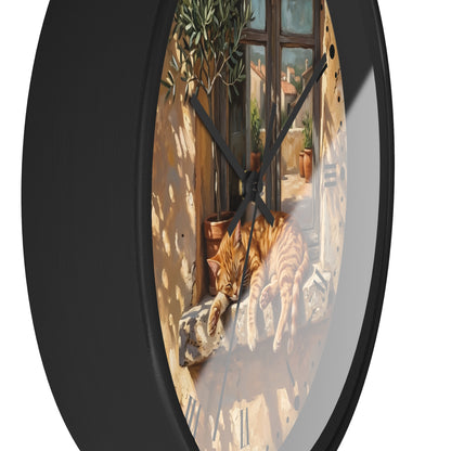 Round wall clock with a black frame and a printed illustration of an orange tabby cat stretching on a windowsill in a sunlit courtyard.