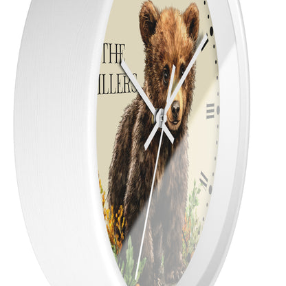 A round wall clock with a white frame and a printed face showing a brown bear illustration on a cream background, with black Roman numerals and white hands.