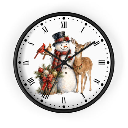 A round wall clock with a black frame and a white face featuring a winter holiday illustration of a snowman, a deer, a red cardinal, and a gift basket with Roman numerals and black hour markers.