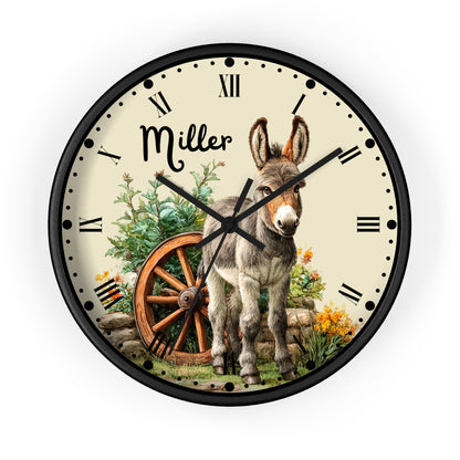 Personalized round wall clock with a black frame, featuring a vintage-style illustration of a donkey, a wooden wagon wheel, flowers, and the name 'Miller' on the cream-colored dial.
