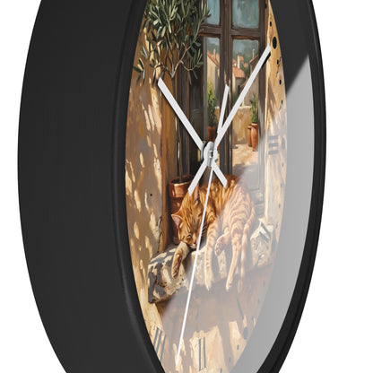 Round wall clock with a black frame and a printed scenic dial showing an orange tabby cat resting on a windowsill in warm sunlight.