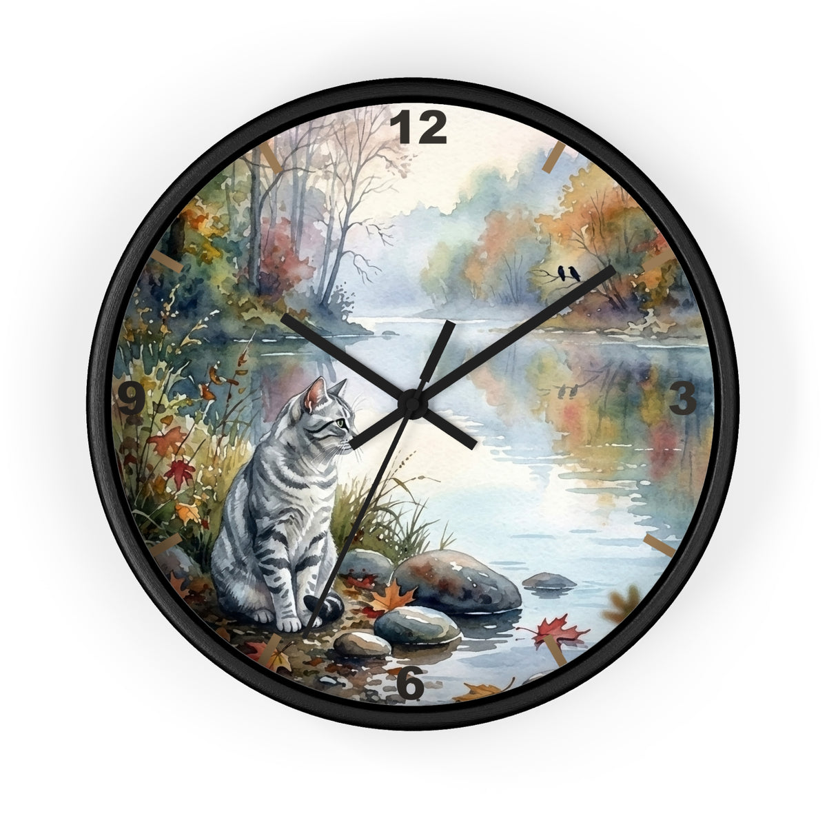 A round wall clock with a black frame and a printed scenic dial showing a gray tabby cat sitting by a calm river in autumn foliage. The clock has black numerals and black hands on a white background.