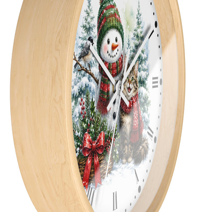 A round wall clock with a light natural wood frame and a white face featuring a winter holiday illustration of a snowman, a cat, a bird, and evergreen trees.