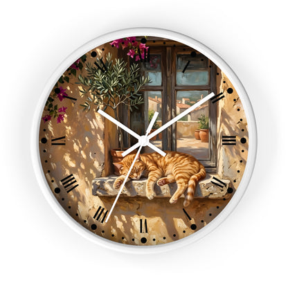 Round wall clock with a white frame and a printed illustration of an orange tabby cat sleeping on a stone windowsill in front of a sunlit Mediterranean-style window. The clock face includes black Roman numerals and white hands, shown against a plain white background.