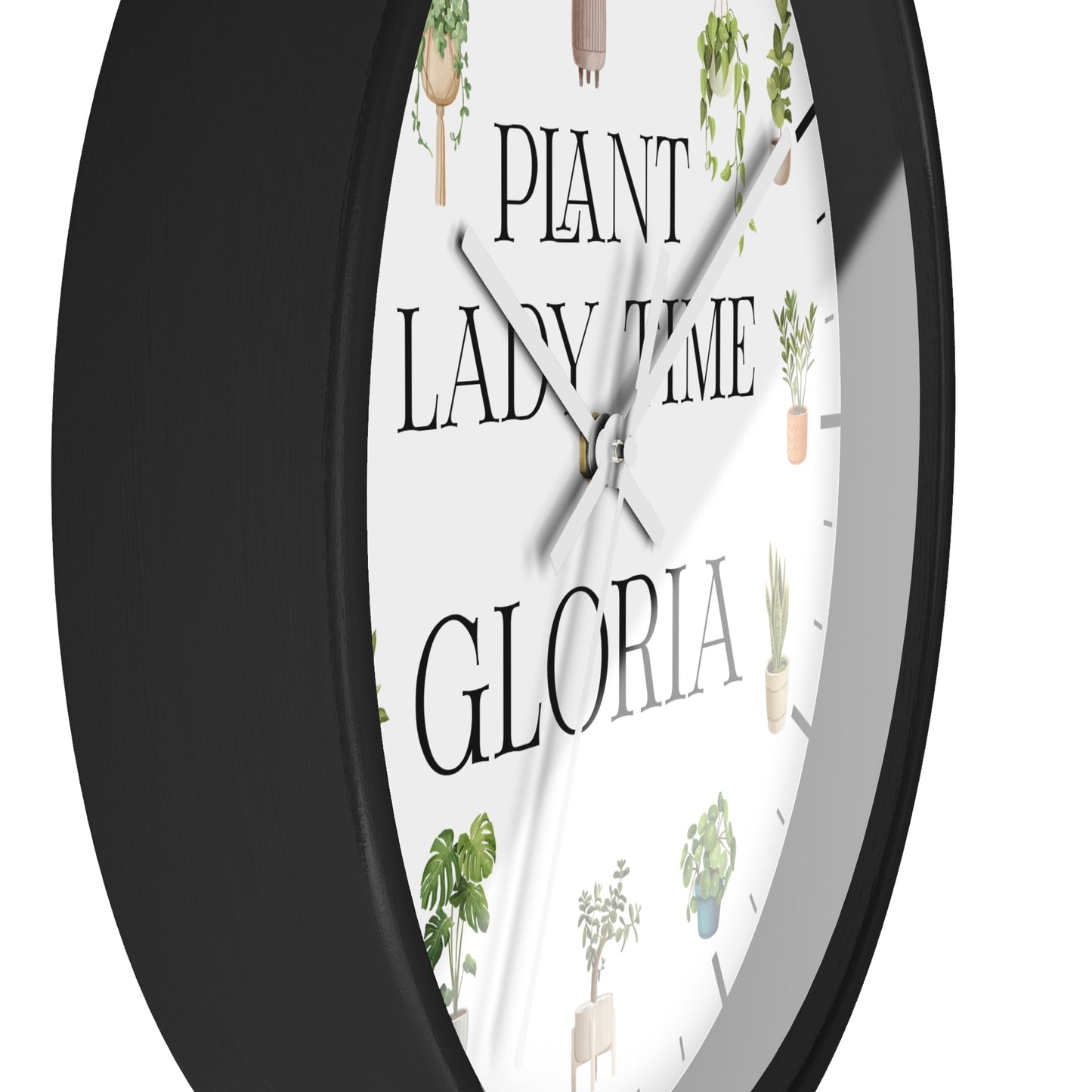 A close-up of a round wall clock with a black frame and a white face featuring the text 'PLANT LADY TIME GLORIA' and small cactus and plant illustrations.