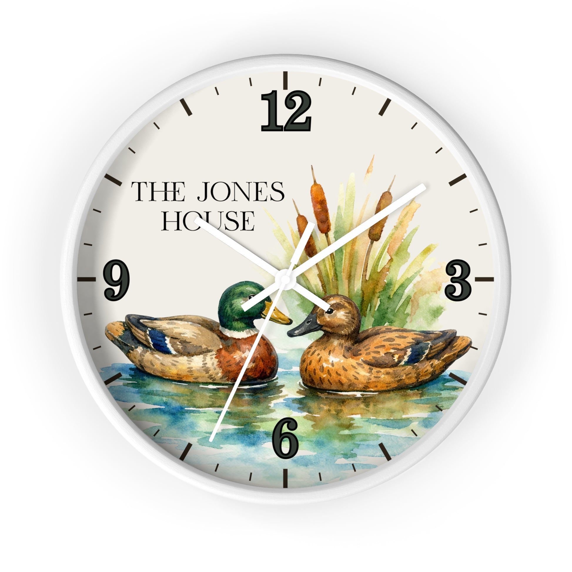 A round wall clock with a white frame and a printed watercolor-style design featuring two ducks on blue water with cattails and the text 'THE JONES HOUSE' on the clock face.