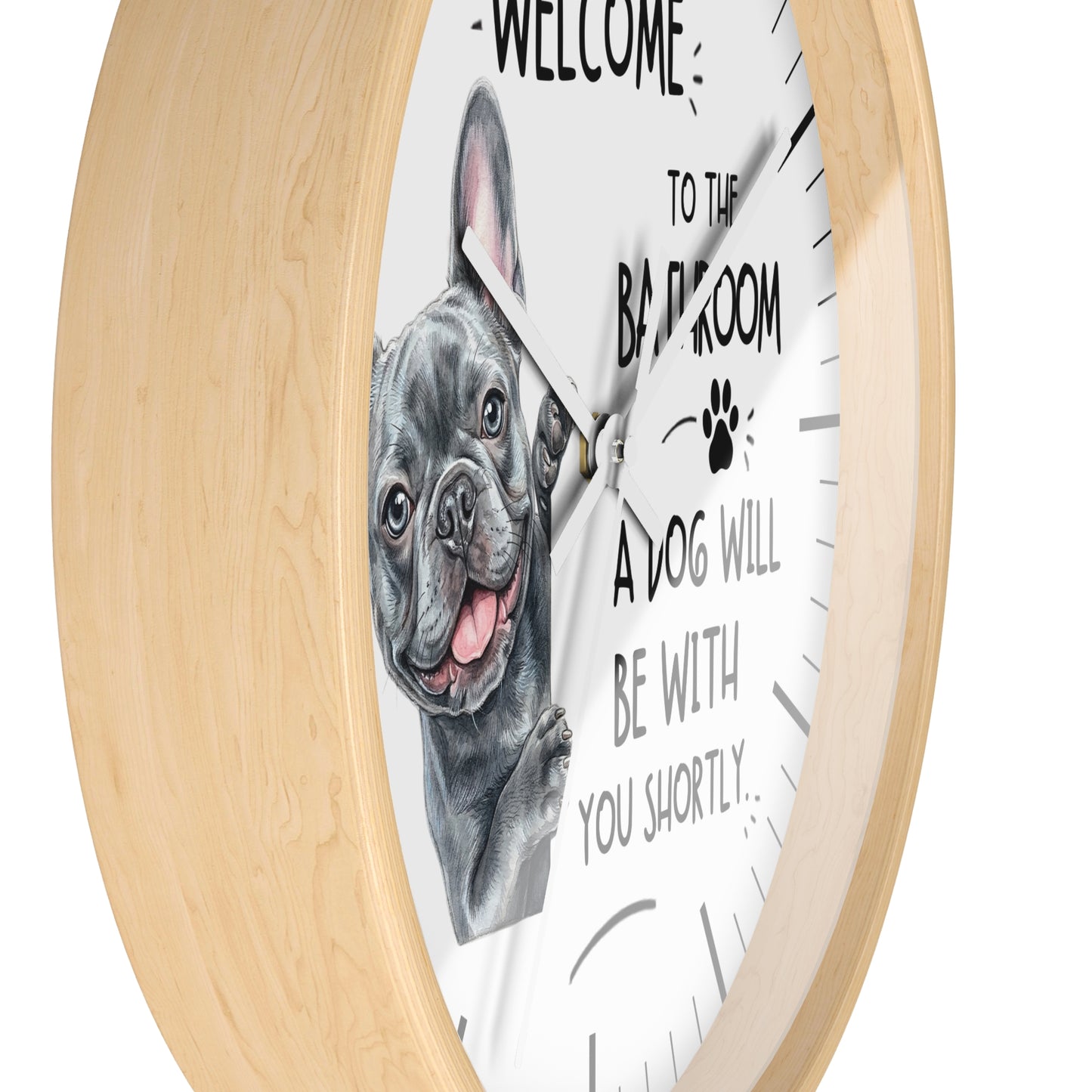 A round wall clock with a light natural wood frame and a white face. The clock features a black and white illustration of a French Bulldog next to the text 'WELCOME TO THE BAR ROOM A DOG WILL BE WITH YOU SHORTLY.