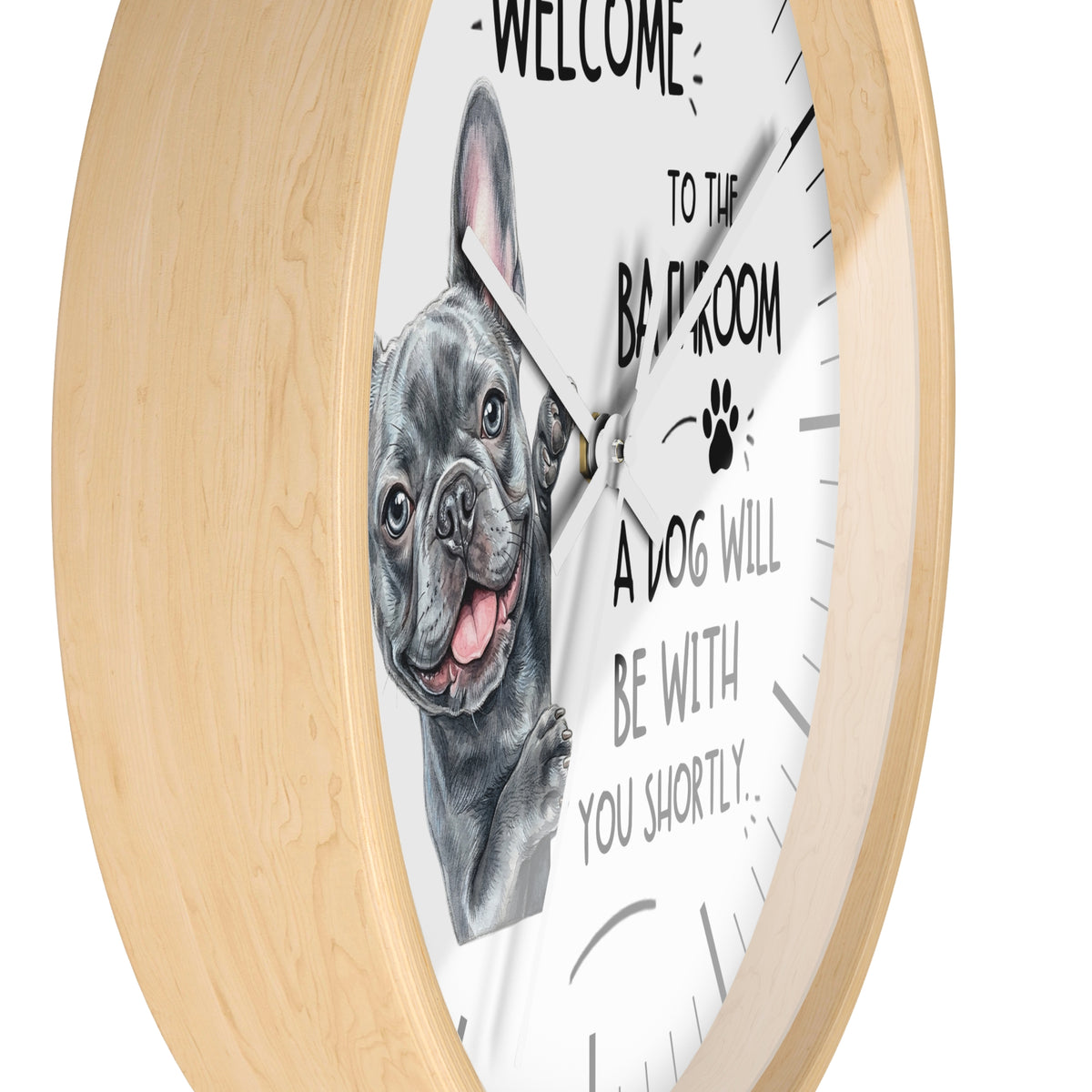A round wall clock with a light natural wood frame and a white face. The clock features a black and white illustration of a French Bulldog next to the text 'WELCOME TO THE BAR ROOM A DOG WILL BE WITH YOU SHORTLY.